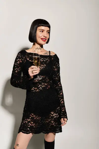 Celebrating with elegance, a tattooed woman raises a glass in chic attire. — Stock Photo