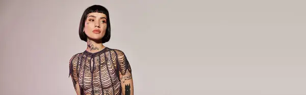 A fashionable woman displays her stunning tattoos in an artistic pose. — Stock Photo