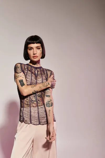 A young woman with striking tattoos poses confidently in fashionable clothing. — Stock Photo