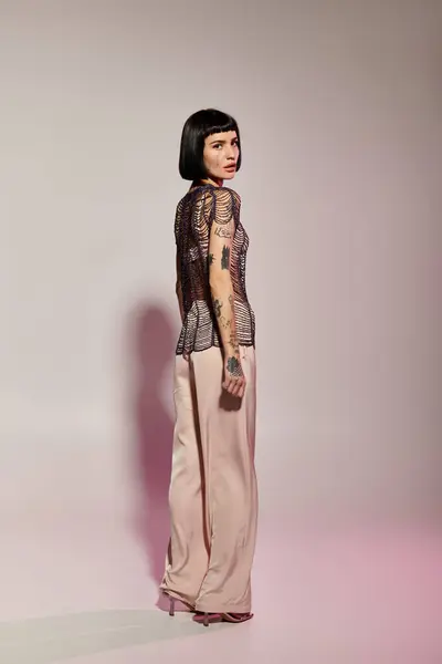 A confident woman poses in chic fashion with striking tattoos and a stylish ensemble. — Stock Photo
