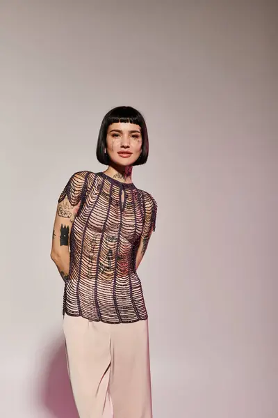 Una mujer de moda exhibe sus tatuajes con un atuendo elegante. - foto de stock