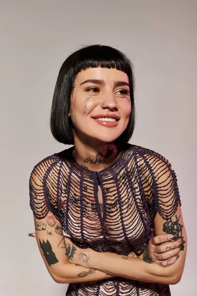 A smiling woman showcases her tattoos while dressed in trendy attire. — Stock Photo