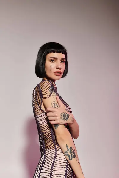 A young woman showcases her tattoos in fashionable clothing, exuding confidence. — Stock Photo