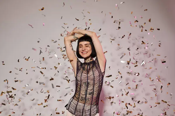 Una donna allegra balla con le braccia alzate come coriandoli colorati la circondano. — Foto stock