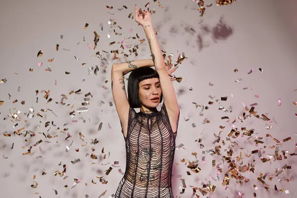 A stylish woman dances joyfully surrounded by shimmering confetti. — Stock Photo