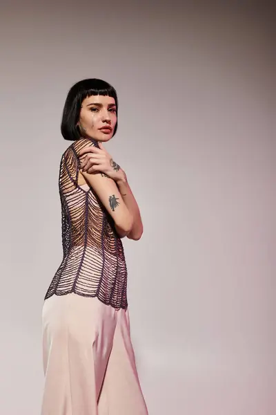 A young woman showcases her tattoos while wearing fashionable clothing. — Stock Photo