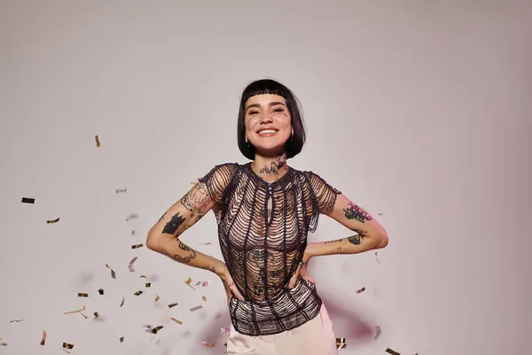 A cheerful woman showcases her tattoos while surrounded by festive confetti. — Stock Photo