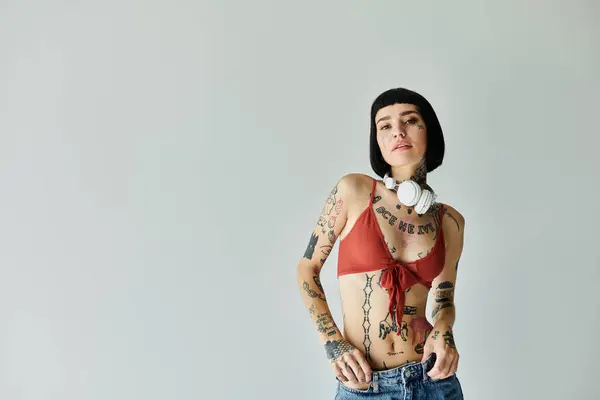 Young woman in trendy attire confidently poses against a neutral backdrop. — Stock Photo