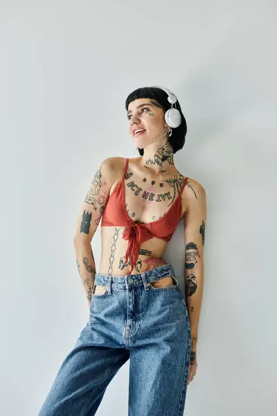 A young woman with tattoos strikes a confident pose while listening to music. — Stock Photo