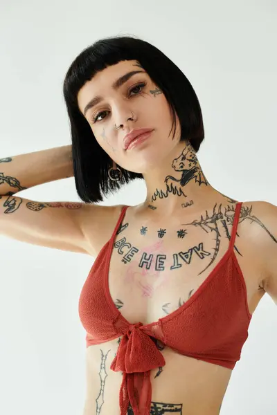 A stylish woman flaunts her tattoos in a chic outfit against a clean backdrop. — Stock Photo