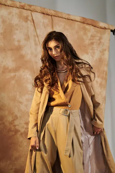 A young and beautiful woman poses elegantly in a chic autumn outfit, embracing the seasonal style in a studio. — Stock Photo