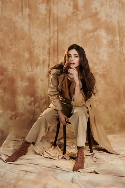 Vestida com uma roupa de outono elegante, uma jovem mulher posa com confiança em um estúdio de tons quentes. — Fotografia de Stock