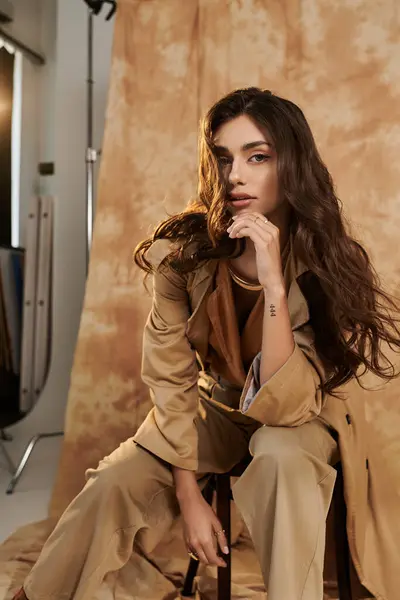 The young woman elegantly poses in a trendy autumn outfit, exuding confidence and charm in a beautifully lit studio. — Stock Photo