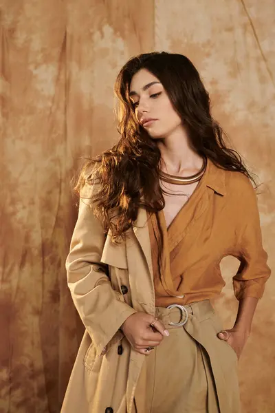 Una giovane donna alla moda posa con grazia in un elegante abito autunnale, incarnando eleganza stagionale tra tonalità morbide. — Stock Photo