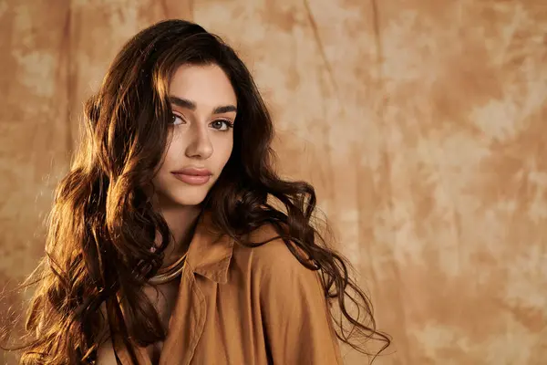 A young woman confidently models a fashionable autumn outfit, surrounded by a warm and inviting studio backdrop. — Stock Photo