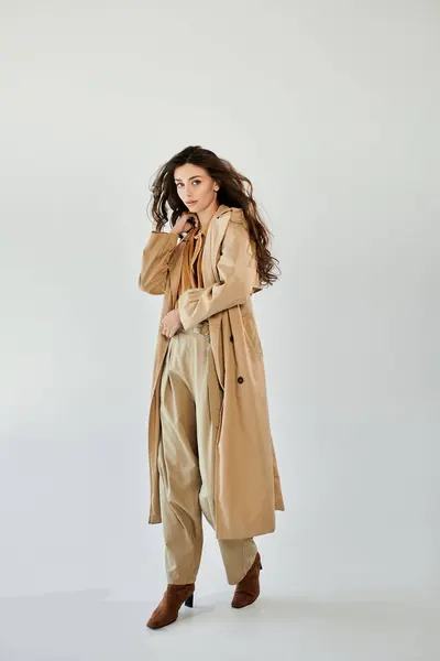 A beautiful young woman poses confidently in a trendy autumn outfit, embodying elegance and style in a bright studio. — Stock Photo
