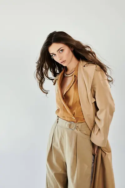 A young and beautiful woman models a chic autumn outfit, exuding elegance and confidence in a minimalistic studio backdrop. — Stock Photo