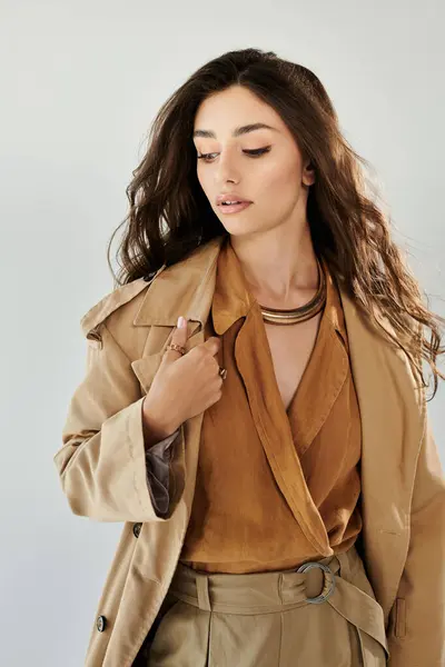 A young, beautiful woman showcases a fashionable autumn outfit, exuding confidence in a stylish studio backdrop. — Stock Photo