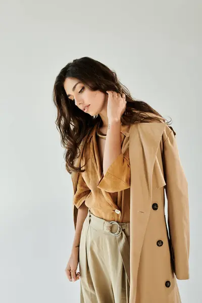 A young woman poses elegantly, showcasing trendy autumn attire in a chic studio against a minimalist backdrop. — Stock Photo