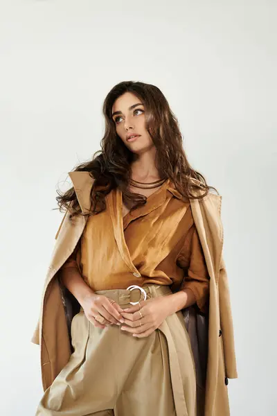 A young and beautiful woman showcases her fashionable autumn attire in a chic studio, radiating style and confidence. — Stock Photo