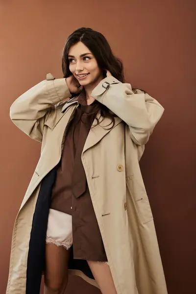 A young woman gracefully poses in a trendy autumn outfit, radiating beauty against a warm backdrop. — Stock Photo