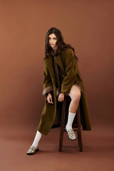 Una mujer de moda modela un elegante atuendo de otoño, encarnando el encanto estacional y la calidez en un elegante entorno de estudio. - foto de stock