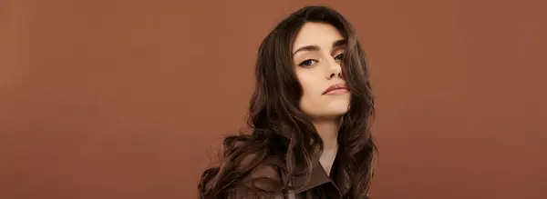 A young woman showcases her fashion sense in an elegant autumn outfit, radiating confidence and warmth in a cozy studio. — Stock Photo