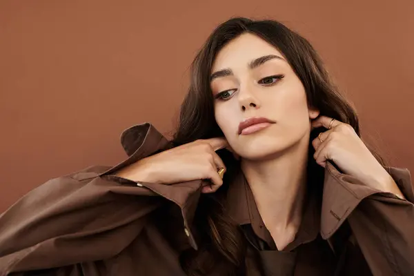 A young woman poses gracefully, highlighting her autumn fashion against a warm studio backdrop, embodying seasonal elegance. — Stock Photo