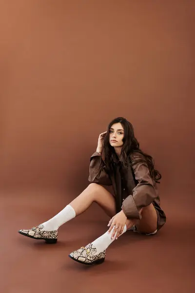 A young woman radiates confidence while posing in a trendy autumn outfit against a rich, warm backdrop, capturing seasonal style. — Stock Photo