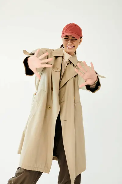 A young woman playfully poses in a chic autumn outfit, radiating joy and style in a minimalistic studio. — Stock Photo