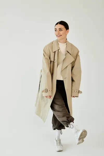 Uma jovem mulher está elegantemente posando em uma roupa de outono na moda, irradiando confiança em um cenário de estúdio sereno. — Fotografia de Stock