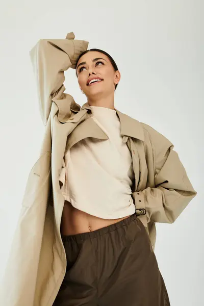 A young woman poses gracefully in a fashionable autumn outfit, radiating confidence in a well-lit studio space. — Stock Photo