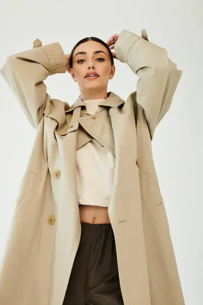 Uma jovem mulher posa confiante em uma roupa de outono, irradiando estilo e elegância dentro de um cenário de estúdio contemporâneo. — Fotografia de Stock
