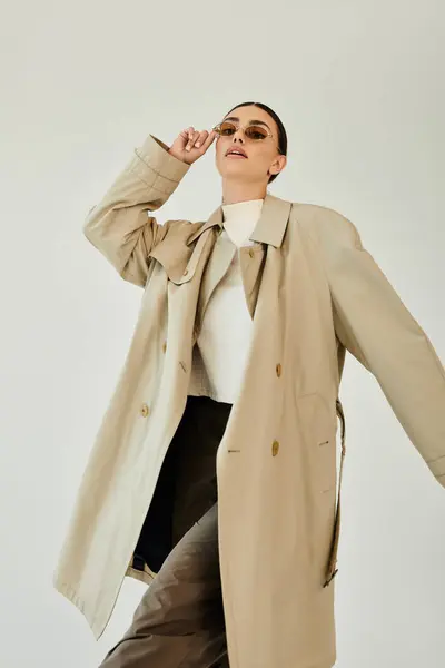 Une jeune femme pose élégamment dans une tenue d'automne tendance, incarnant l'élégance saisonnière dans un décor de studio propre. — Photo de stock