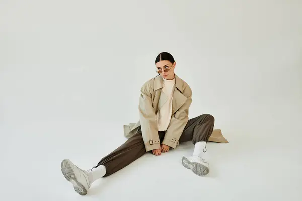 Une jeune femme pose avec confiance dans une tenue d'automne tendance, mettant en valeur un mélange de style et de confort dans un studio. — Photo de stock