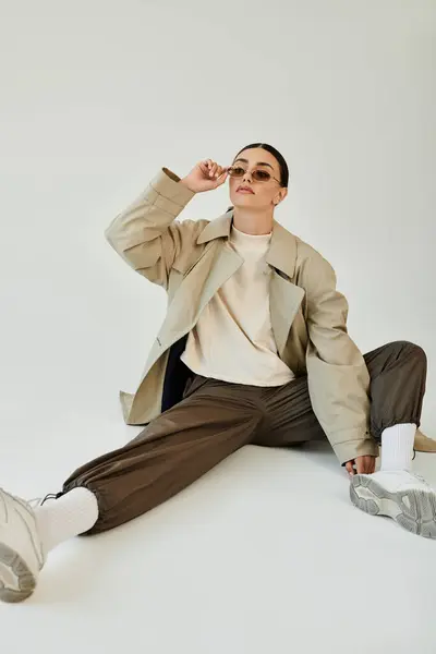 A young woman dons a chic autumn ensemble, exuding confidence while posing stylishly in a minimalist studio. — Stock Photo