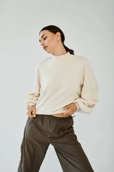 Una mujer joven posa con confianza en un traje de otoño elegante, mezclando elegancia y comodidad en un entorno de estudio contemporáneo. - foto de stock