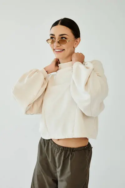 Una joven mujer irradia confianza, posando con elegancia en su atuendo de otoño de moda dentro de un ambiente cálido estudio. - foto de stock