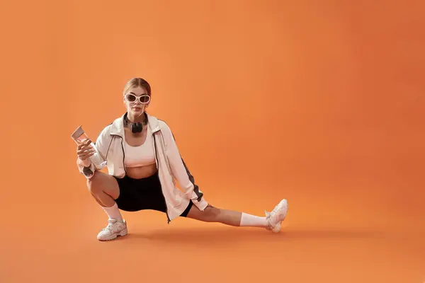 A talented athlete shows strong emotions while stretching in bold orange surroundings. — Stock Photo