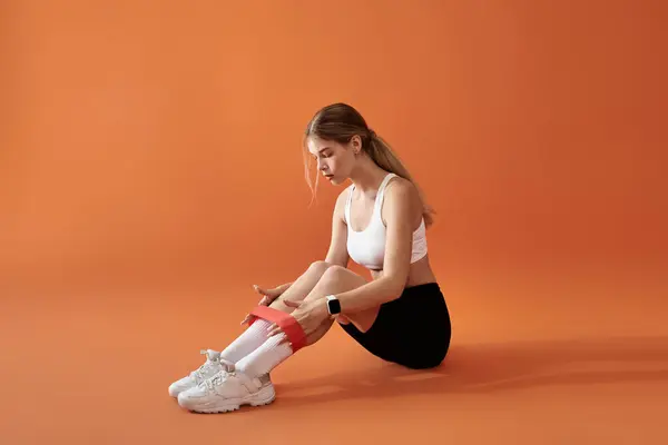A dedicated athlete trains with a resistance band, perfecting her form against a bright backdrop. — Stock Photo