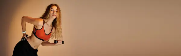A passionate athlete expresses her dedication while lifting dumbbells in an artistic studio. — Stock Photo