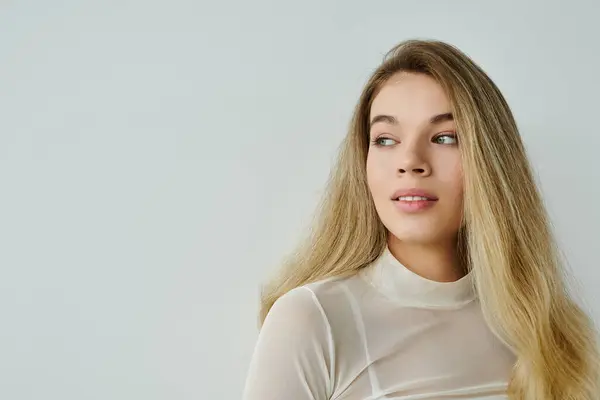 Una giovane donna dai capelli lunghi trasuda calma e bellezza in uno spazio minimalista. — Foto stock