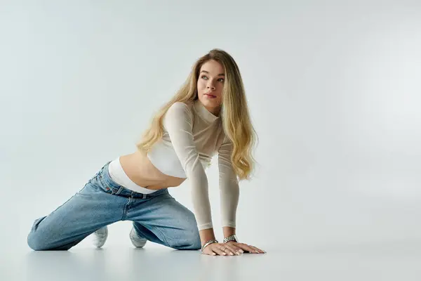 Una joven se arrodilla con gracia, mostrando su elegante atuendo en un entorno sereno. - foto de stock