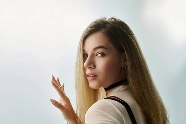 Una giovane donna guarda indietro con un sorriso morbido, illuminata da una luce dolce in un ambiente artistico. — Foto stock