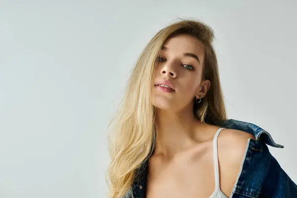 A stunning young woman showcases her natural beauty while wearing a stylish denim jacket. — Stock Photo