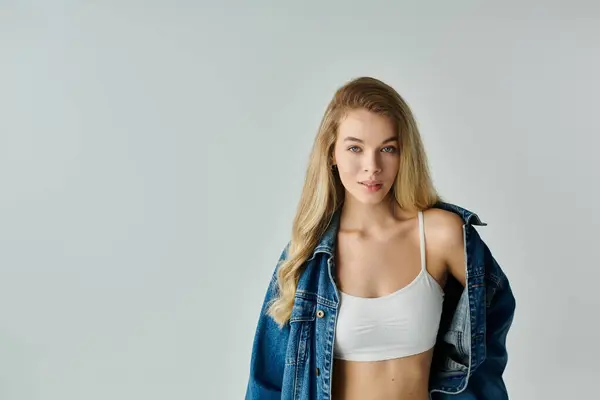 A young woman stands gracefully, exuding confidence in her stylish outfit against a soft backdrop. — Stock Photo