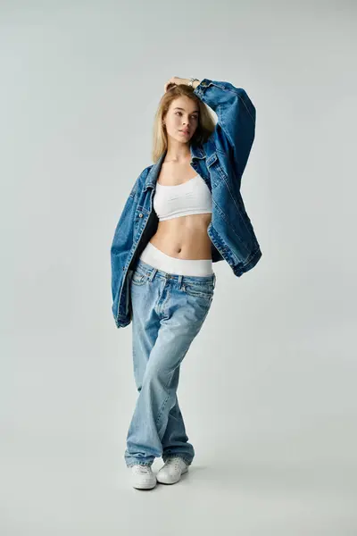 A young woman with flowing hair poses confidently in a trendy denim outfit, exuding elegance. — Stock Photo