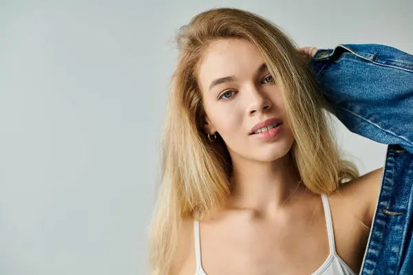 A young woman smiles playfully while posing in a casual, stylish outfit against a light background. — Stock Photo