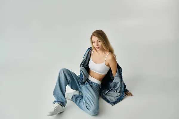 A youthfully radiant woman sits stylishly on the floor, showcasing casual fashion and confidence. — Stock Photo