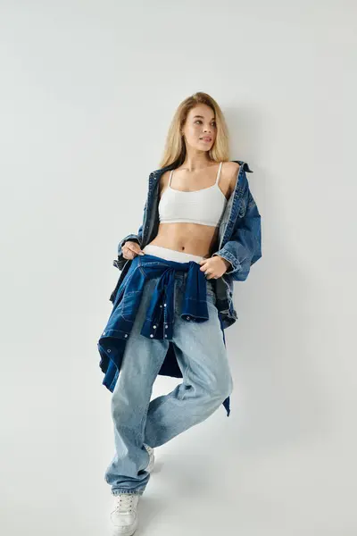 A young woman in stylish denim stands with poise, showcasing a blend of fashion and attitude. — Stock Photo